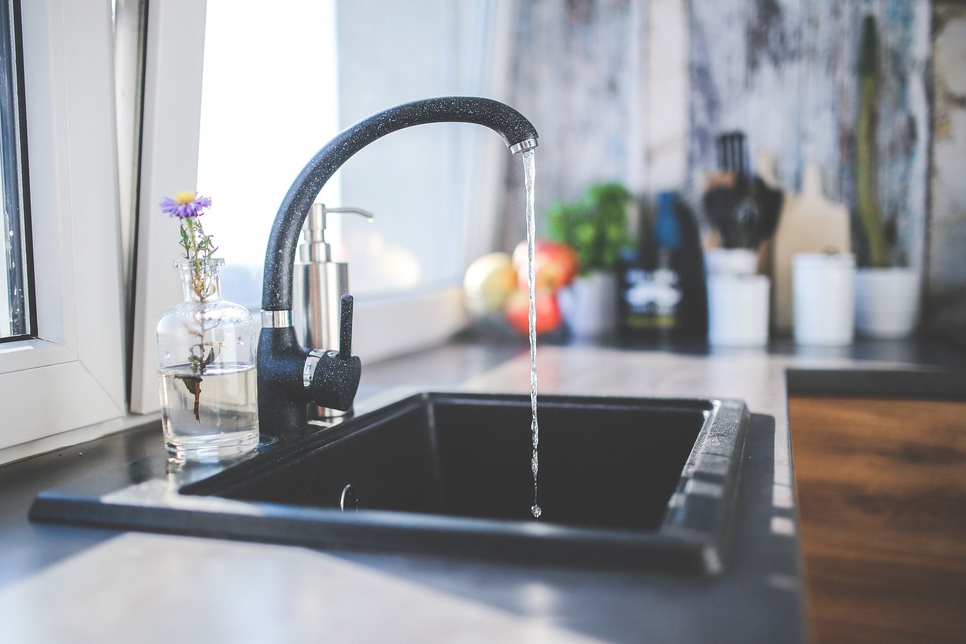A kitchen sink with water trickling out of the spout