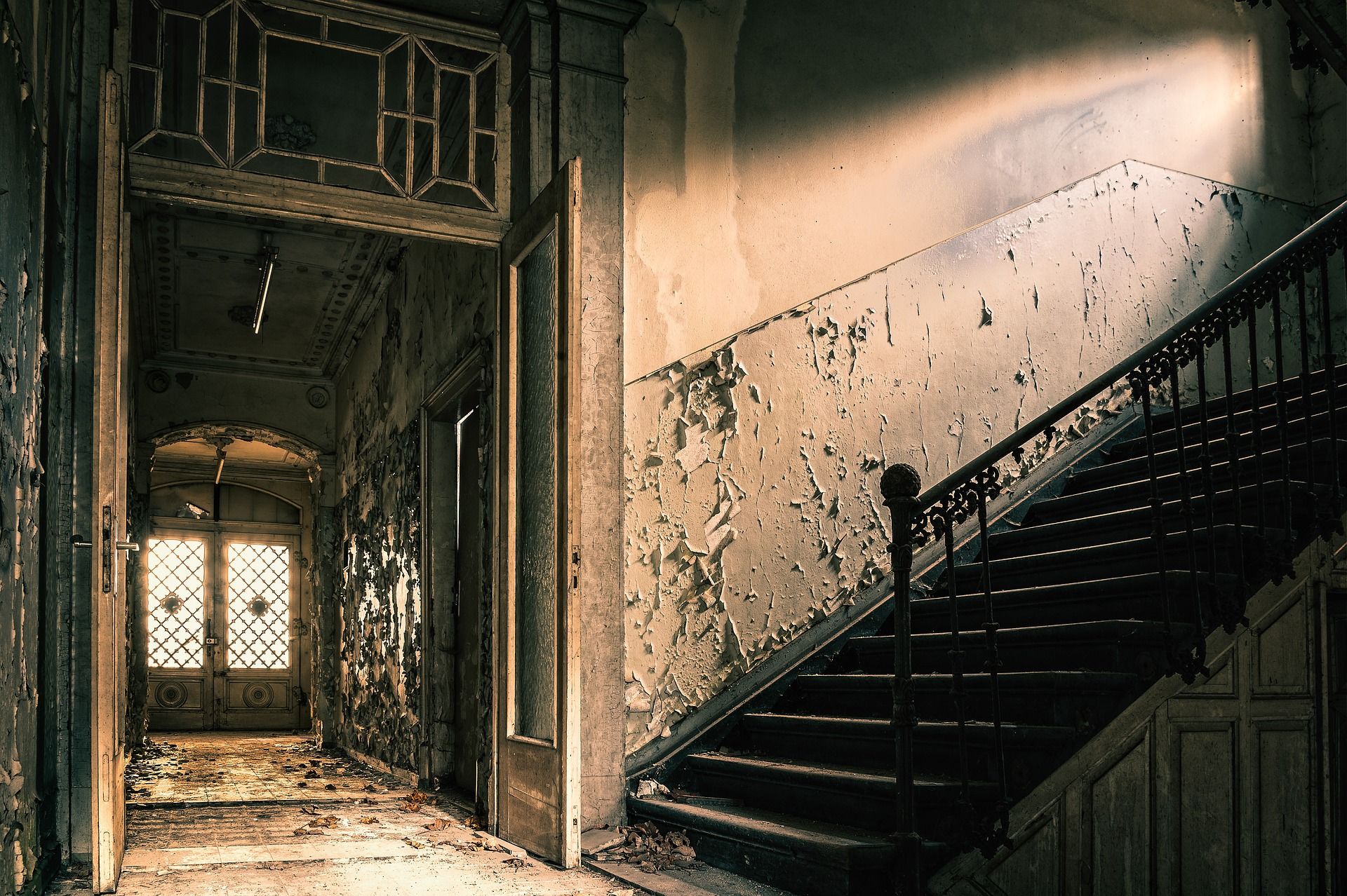 The foyer, entry hallway, and a portion of stairs in a haunted, run down house.