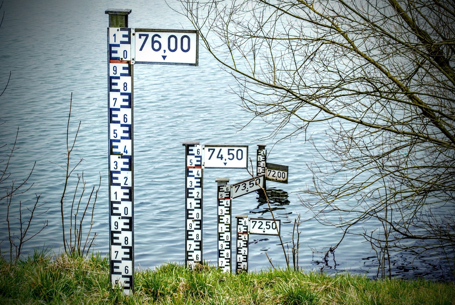 Water height measurement signs coming out of a lake showing how the water is decreasing.