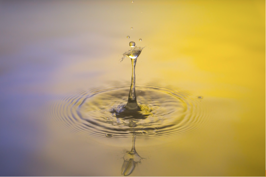 Water in blues and yellows with a drop making a ripple.