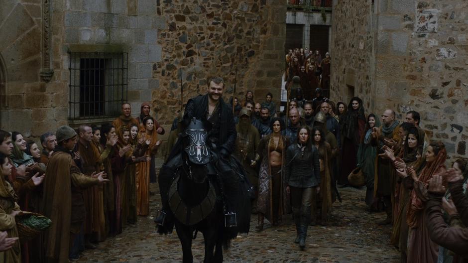 Euron rides on his horse with Ellaria, Yara, and Tyene being pulled behind him while the crowds cheer.