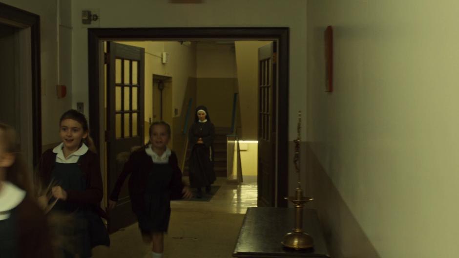 A number of the children at the orphanage run down the hall followed by one of the nuns.