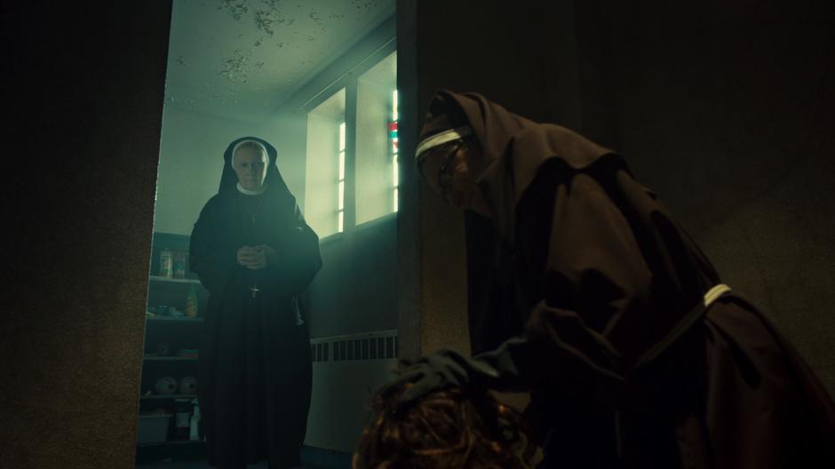 One of the nuns watches as another forces Helena's head into a bucket of bleach.