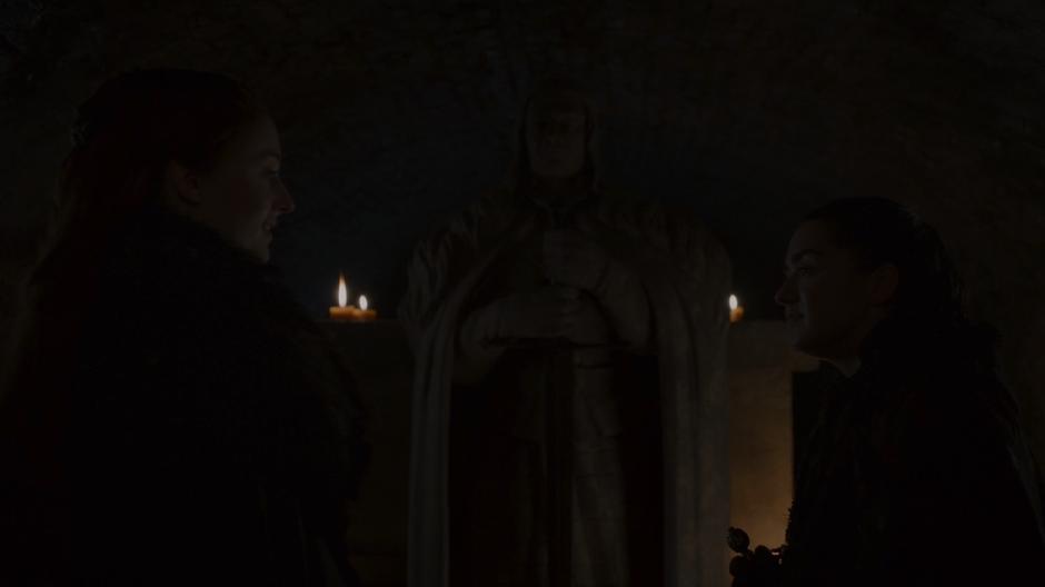Sansa and Arya talk in front of their father's statue.