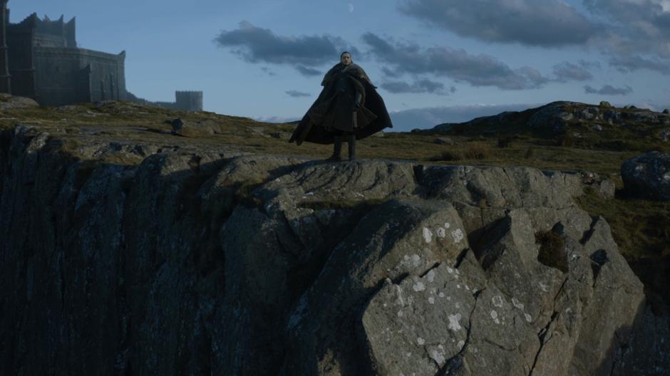 Jon stands on the edge of the cliff and watches as Drogon returns.