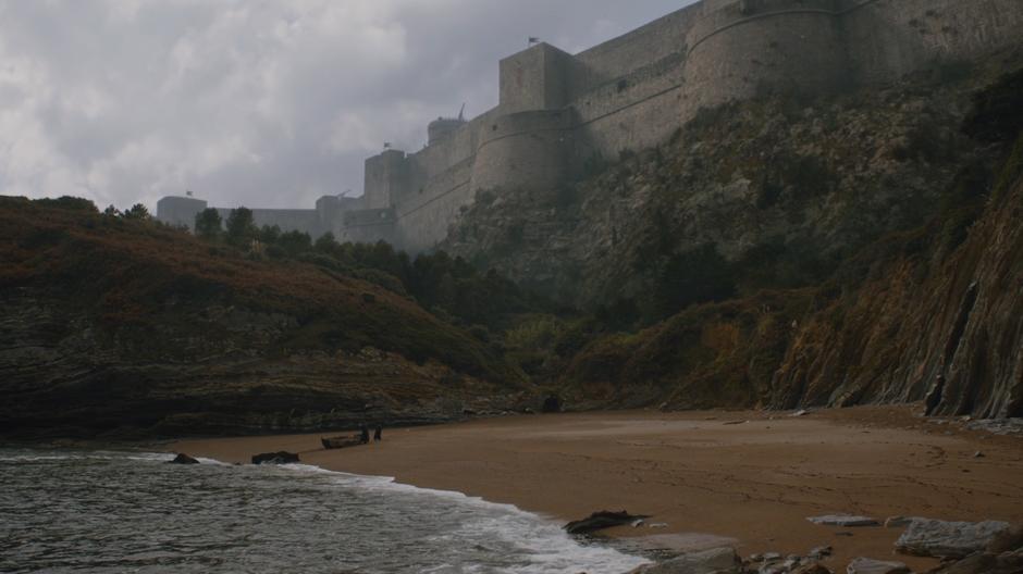 Davos pulls the boat up onto the beach while Tyrion looks up at the walls of the city.