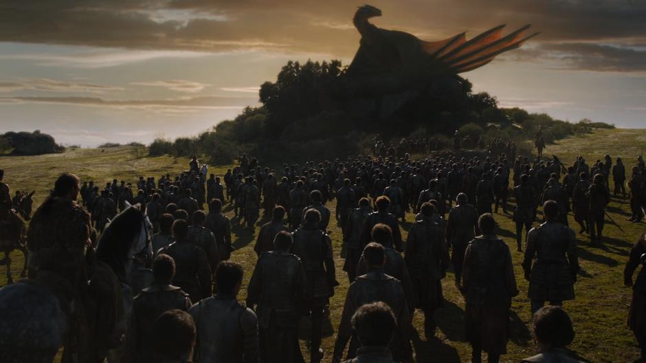 The Lannister soldiers gather in front of the large rock where Drogon is perched and are addressed by Daenerys.