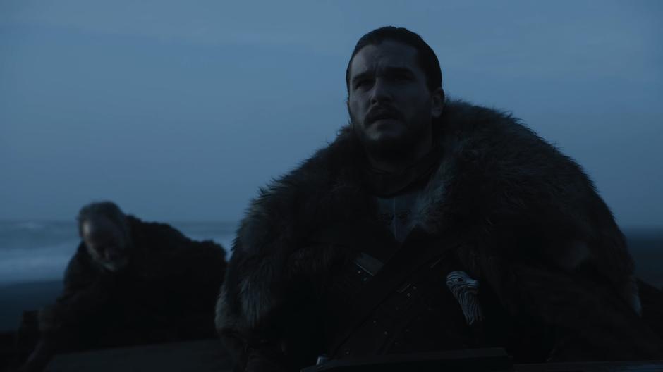 Jon looks up at Eastwatch-by-the-Sea while Davos unloads his stuff from the boat.