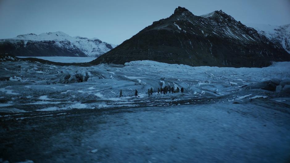 The party walks across a glacier running between several mountains.