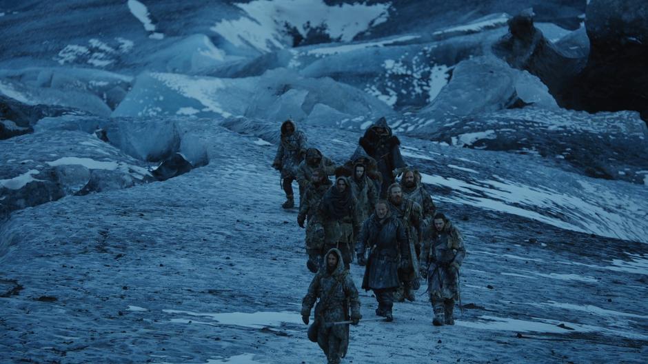 A wildling leads the party as they walk across the glacier.