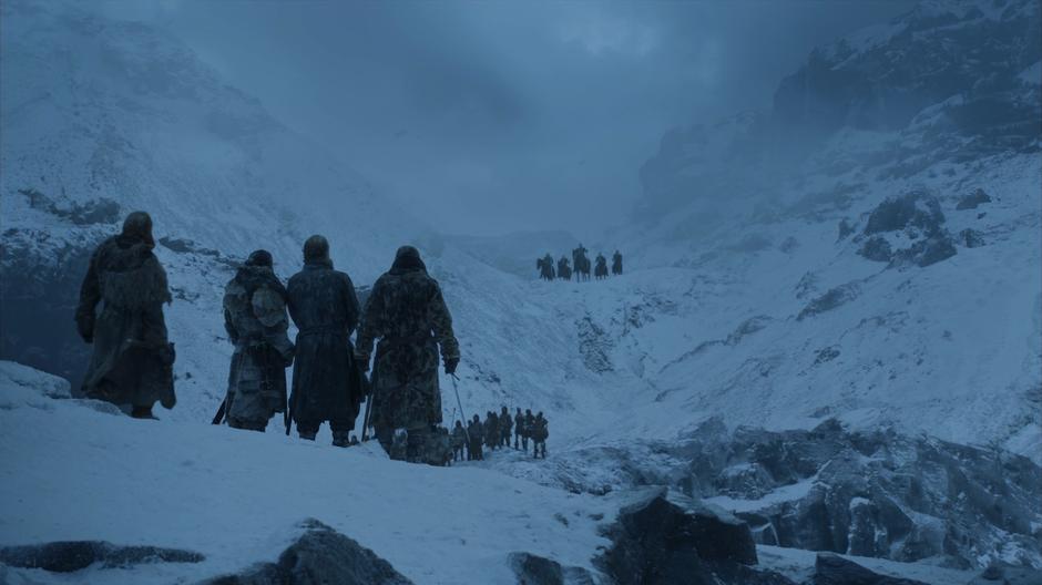 The guys on the island look up to a nearby cliff where the Night King is watching from.