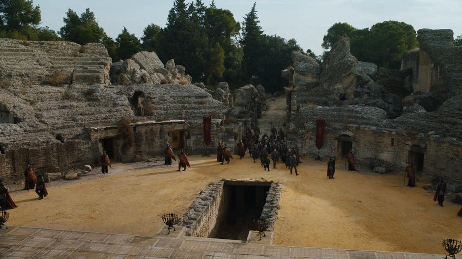 Daenerys and Jon's entourages enter the Dragonpit escorted by Lannister soldiers.