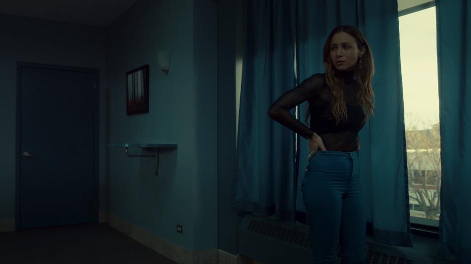 Waverly looks back at Nicole and Shae while standing at the window of the room.
