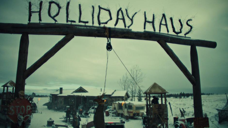 A revenant swings on a cord strung from the gate which now reads *Holliday Haus*.