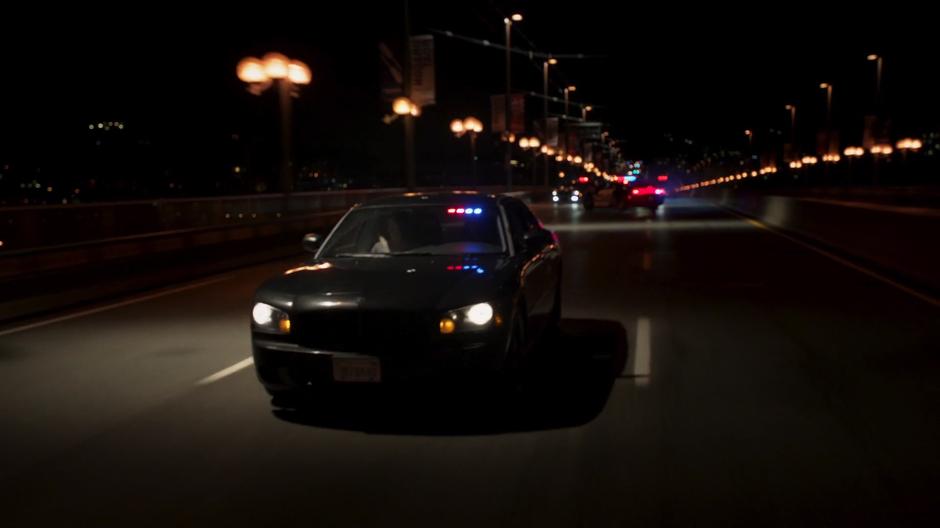 Maggie and Alex drive after the truck while a cop car spins out behind them.