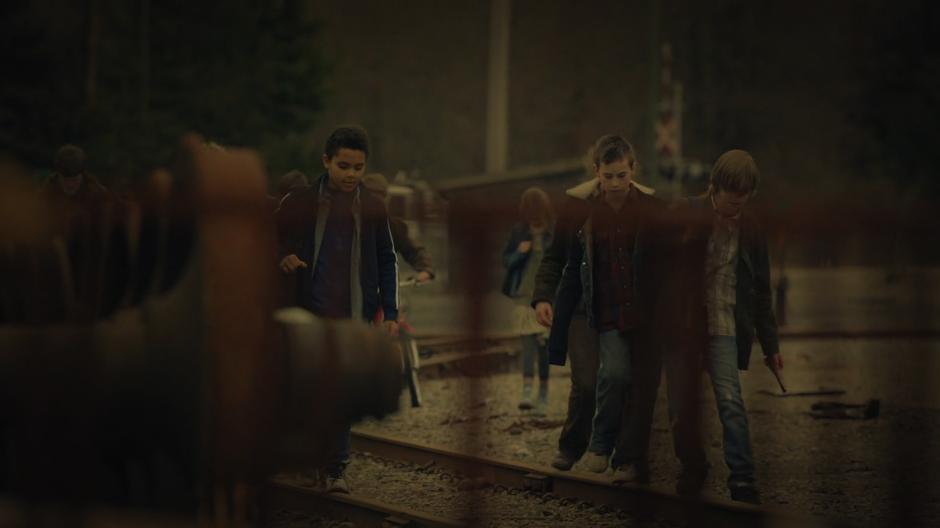 A group of kids walk down the tracks.