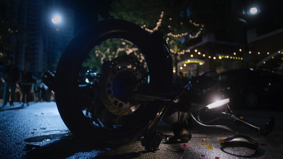 The motorcycle lies in the street after being hit by a car.