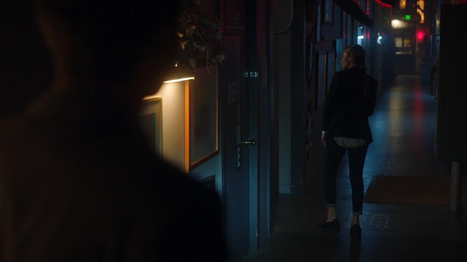 Lucifer watches as Chloe walks ahead searching the sound stage.