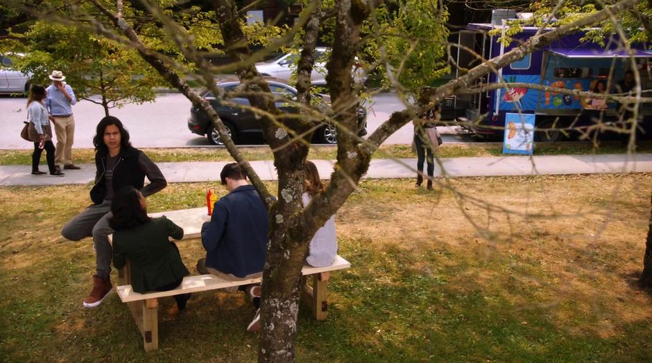 Cisco, Iris, Barry, and Caitlin sit at the picnic table after their laser tagging adventure.