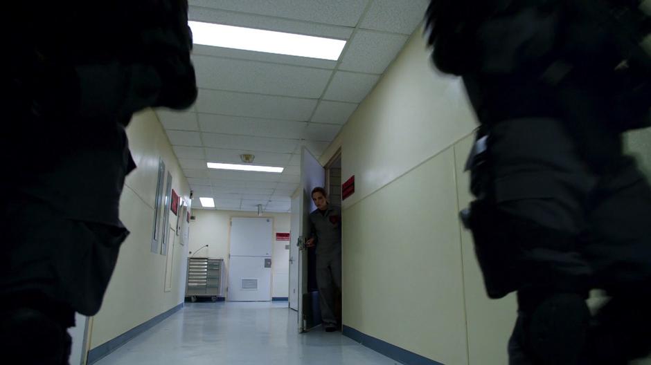Sara peaks out from the maintenance closet after two of the A.R.G.U.S. guards walk past.