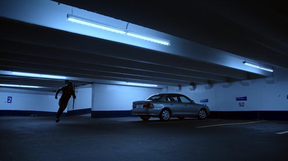 Diggle runs through the parking garage chasing after Alex Faust.