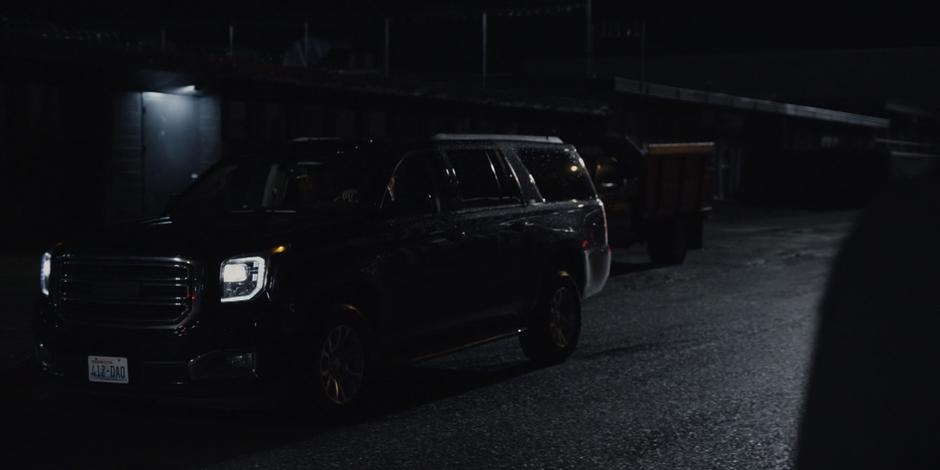 The driver of one of the suspicious black SUVs watches Grant as he drives away.