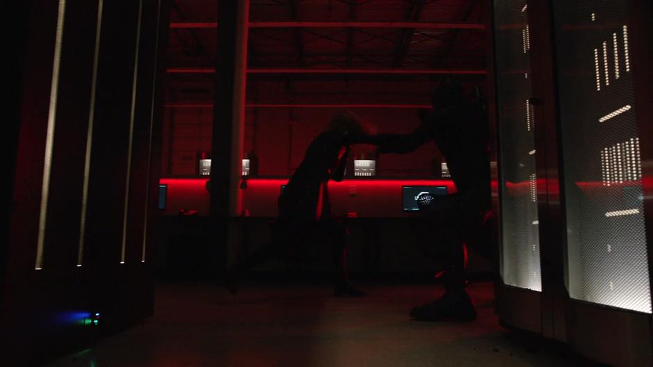 Diggle fights with Black Siren in a room bathed in red light.