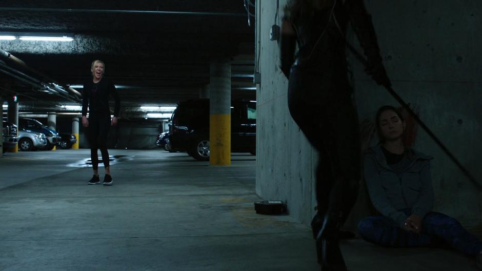 Black Siren fires her sonic scream at Dinah who is standing over the body of Jenny Johnson.