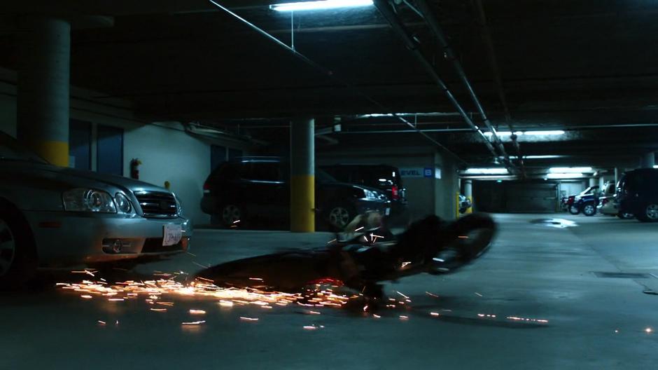 A motorcycle flies across the garage after being thrown by Dinah.
