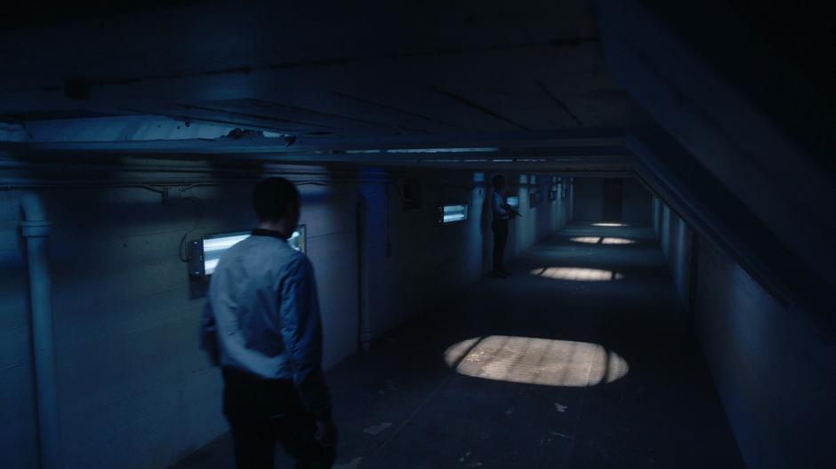 A Black Wing agent walks down the tunnel while another stands guard.