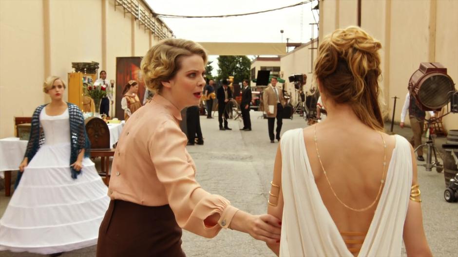 A studio worker escorts Helen to the sound stage as everyone stares at her.