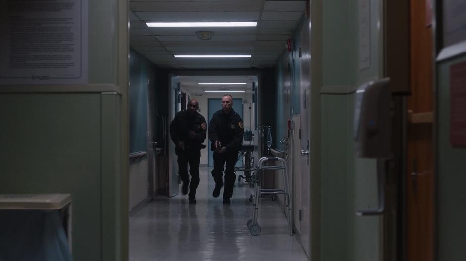 Two police officers run down the hallway to check out the ruckus.