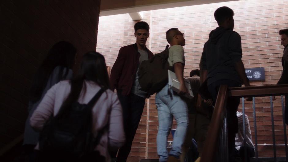 Barry walks through the flow of students towards the stairs.