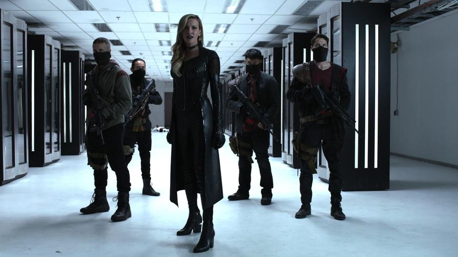 Black Siren stands in the lab and prepares to break open the case.