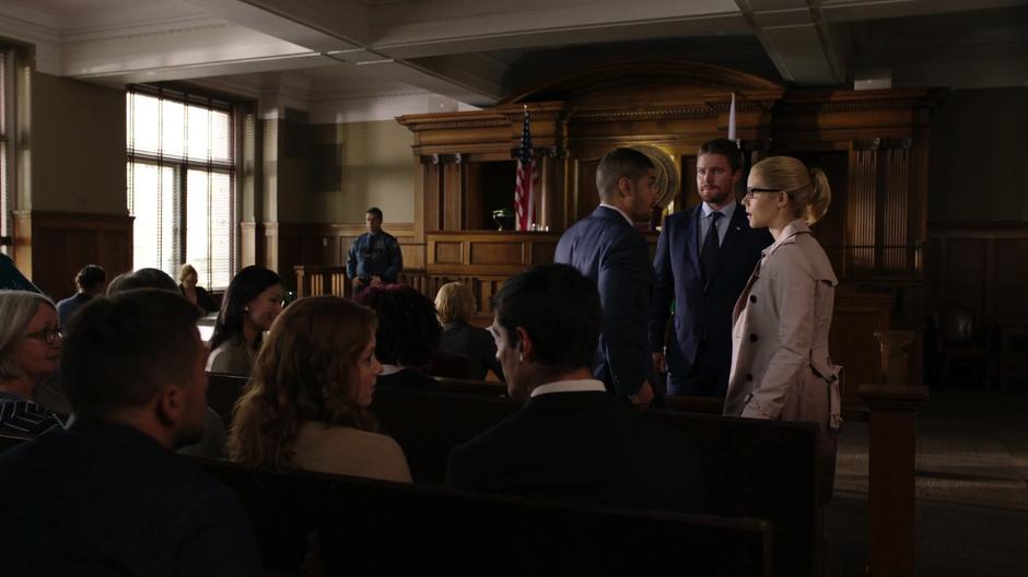 Felicity enters the courtroom and talks with Rene and Oliver.