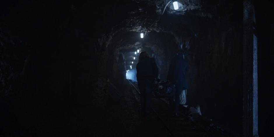 Philip and Grant carry the warhead down the mine tunnel.