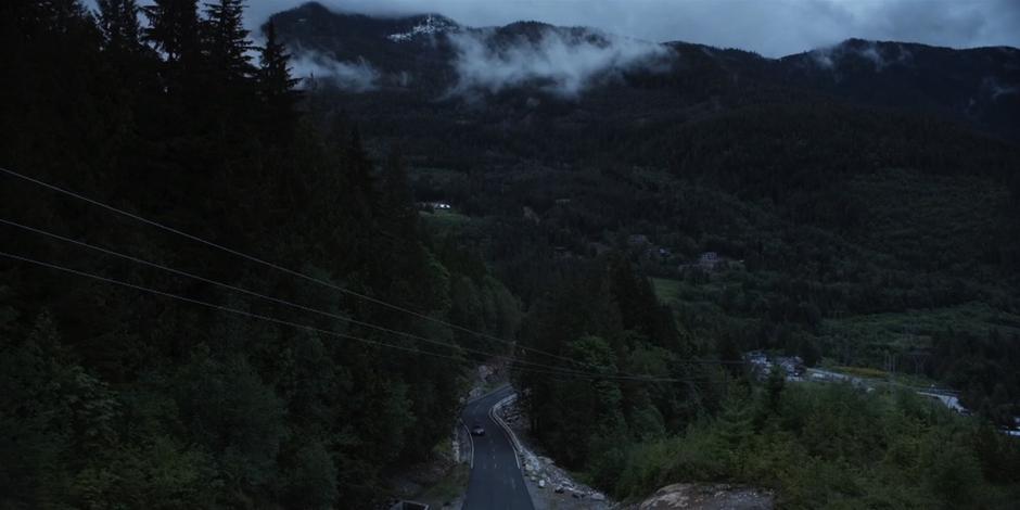 The car drives up the road towards the checkpoint.