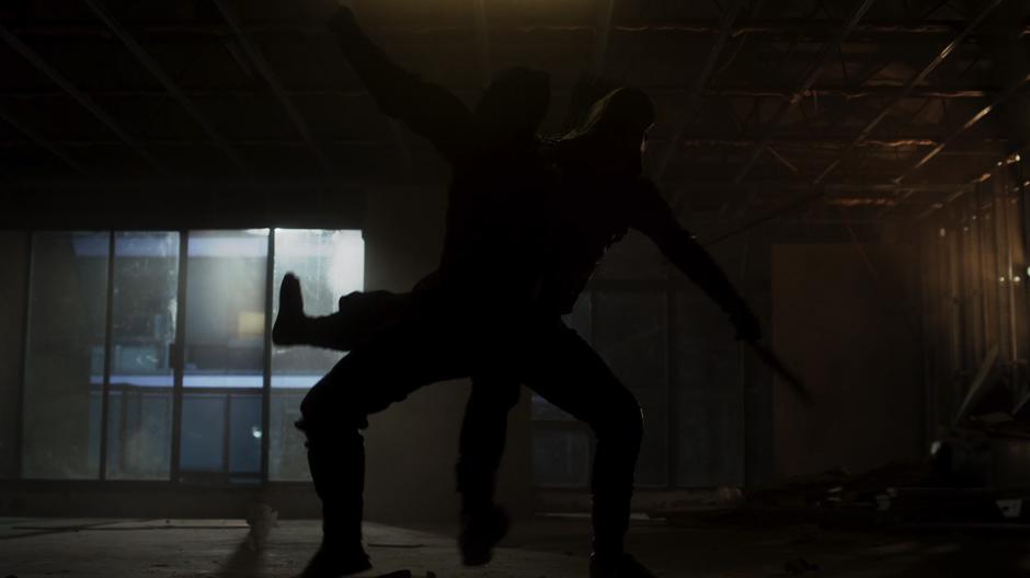 Oliver fights a ninja in an empty building.