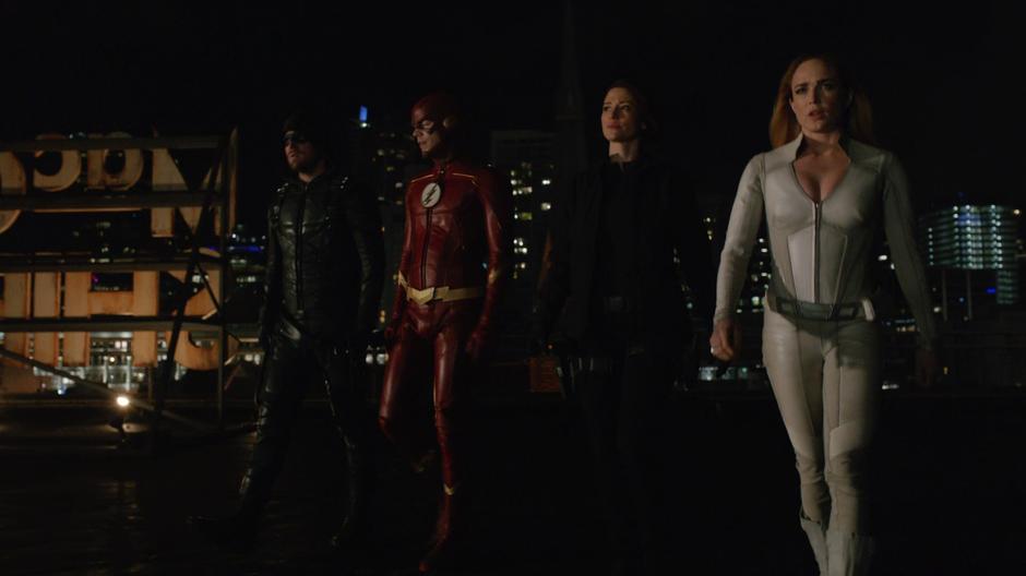 Oliver, Barry, Alex, and Sara walk across the roof of the shipping facility.