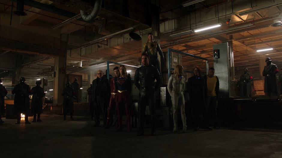 Stein, Barry, Kara, Oliver, Sara, Alex, and Jax are lined up with collars while Thawne stands over them and Earth-X soldiers surround them.