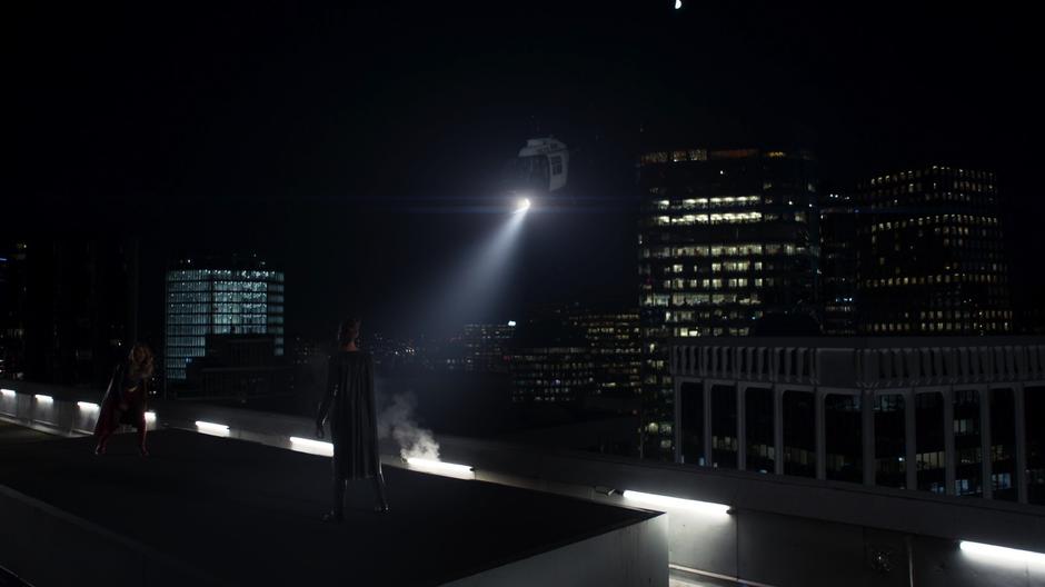 Kara lands on the roof where Reign is waiting while a helicopter circles around.