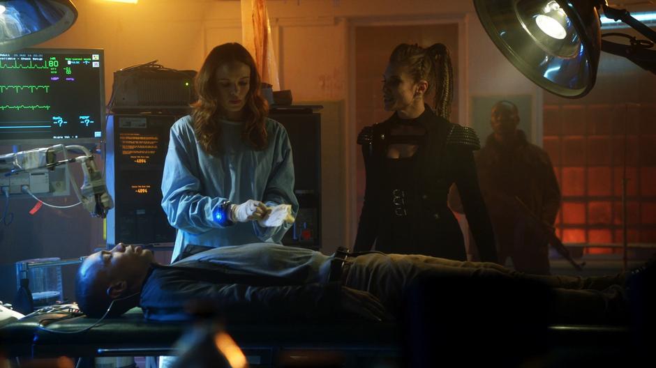 Amunet threatens Caitlin as she puts on gloves before the surgery.