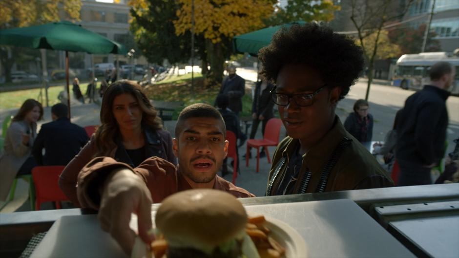 Dinah and Curtis watch Rene grab a burger from the food cart.