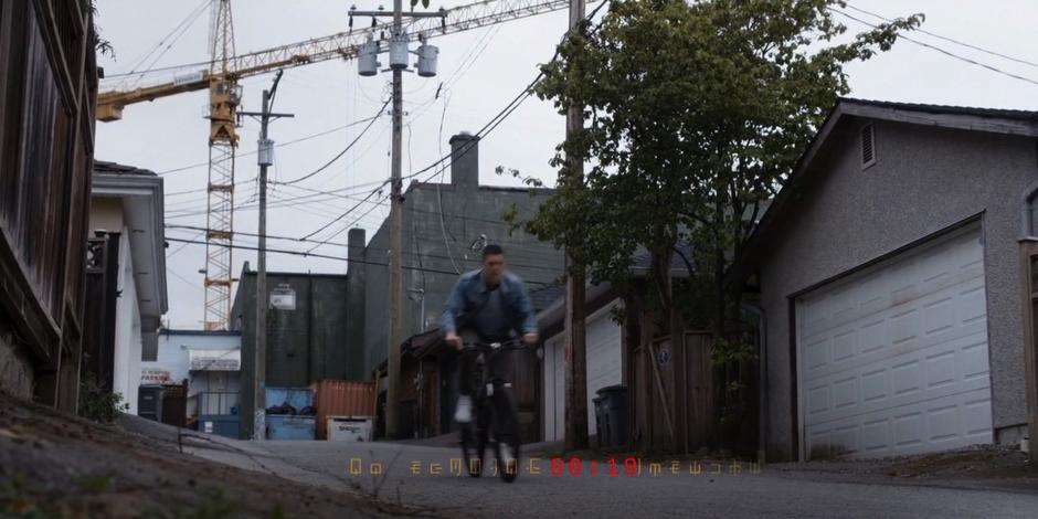 Trevor bikes down another alley with a construction crane in the background as the timer counts down to Kyle's recorded death.
