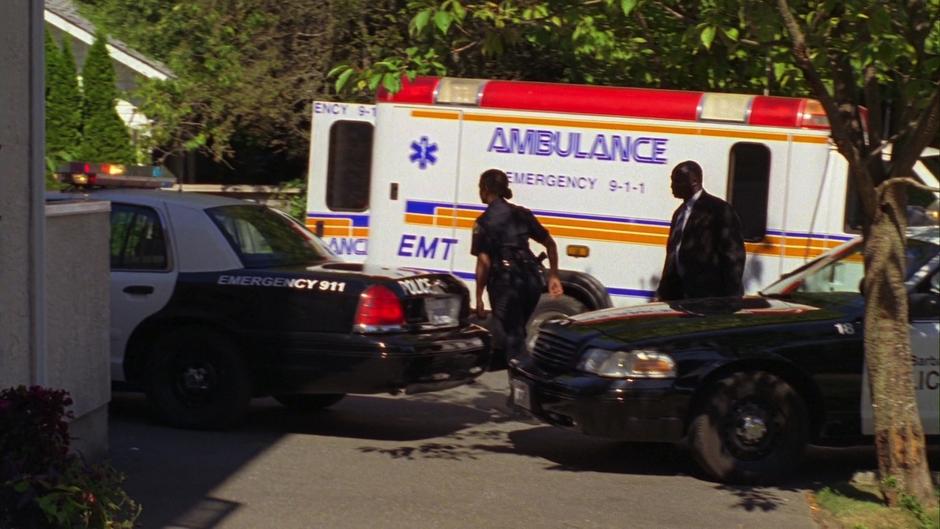 Several police cars and an ambulance sit outside the apartment building.