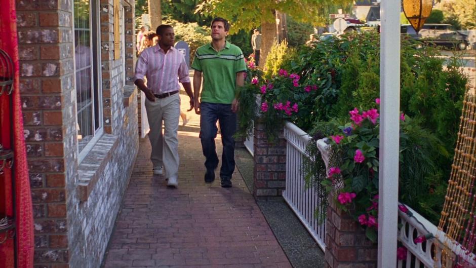 Gus and Shawn walk down the sidewalk to the entrance of the restaurant.