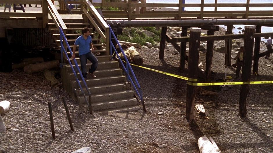 Shawn runs down the stairs to the beach where the crime scene tape is spread.