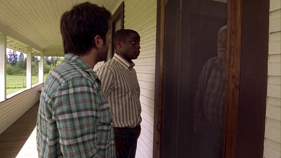 Shawn and Gus talk to Walker through the screen door on the farmhouse.