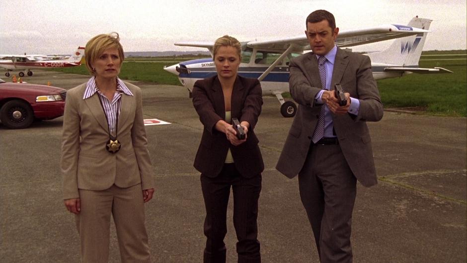 Vick stands by while Juliet and Lassiter point their guns at Lindsay Leikin on the ground.
