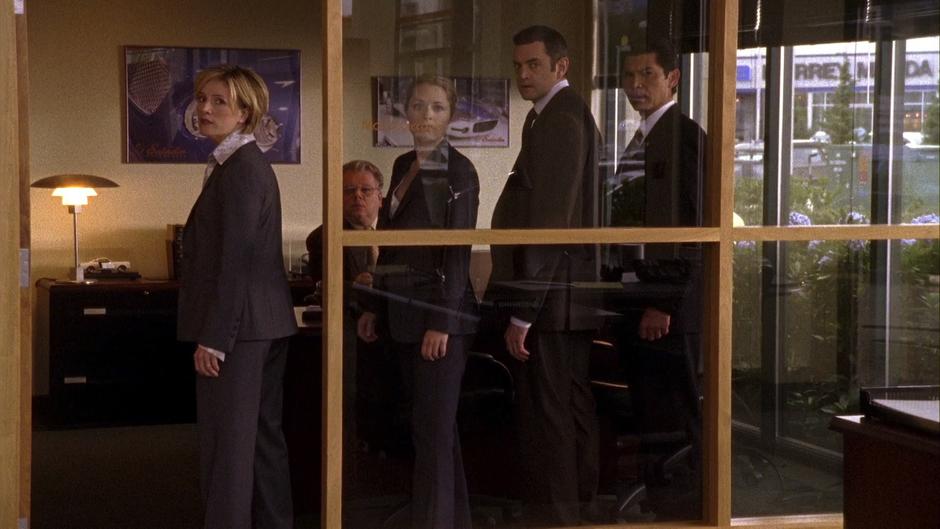 Vick, Juliet, Lassiter, and Ewing look out from the manager's office.